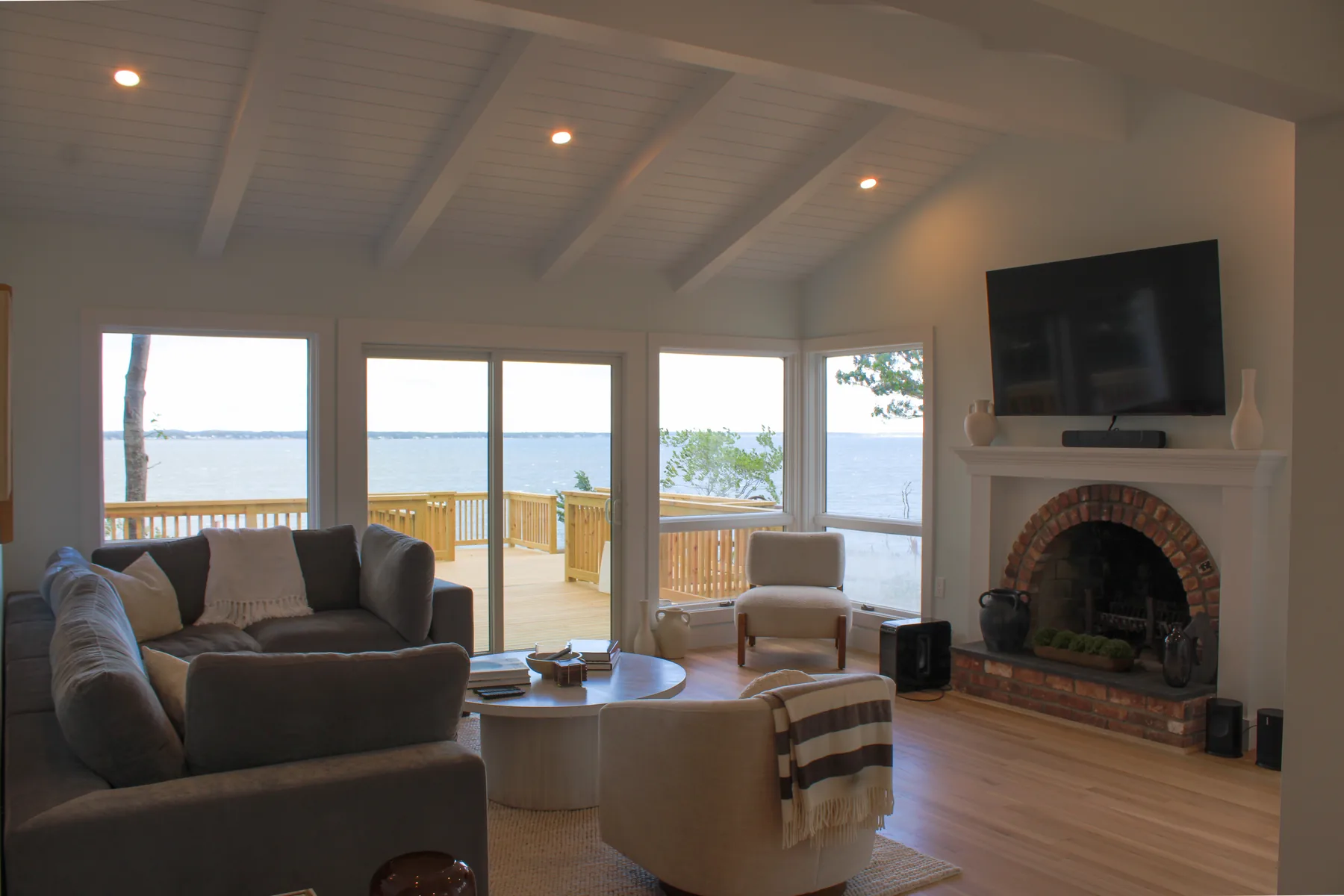 Living room at 46 Red Cedar Point Road with a brick fireplace and sliding doors to a bay-view deck